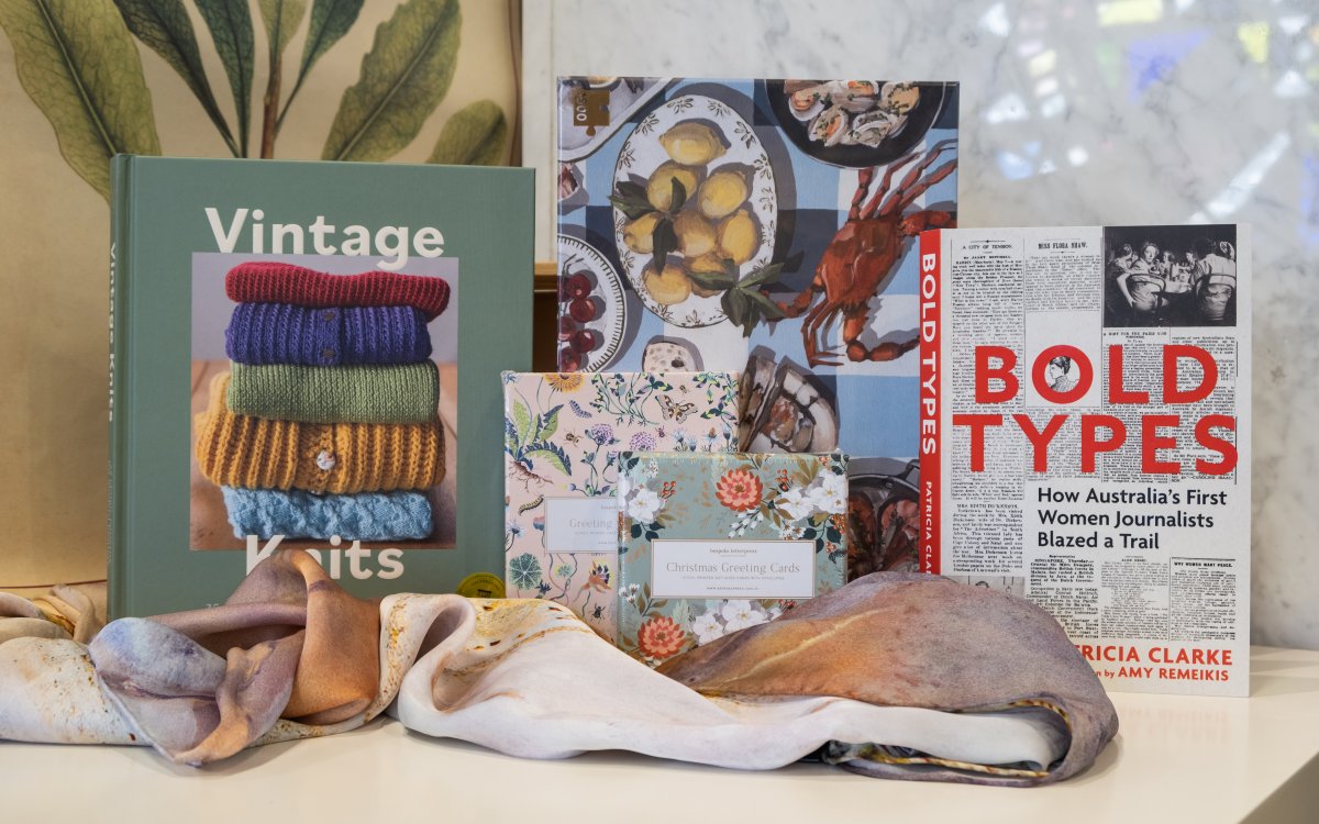 'Vintage Knits' and 'Bold Type' books sitting either side of a vintage blue puzzle  and two boxes of cards, one pink floral and another green floral. A pastel colour scarf lays in front. 