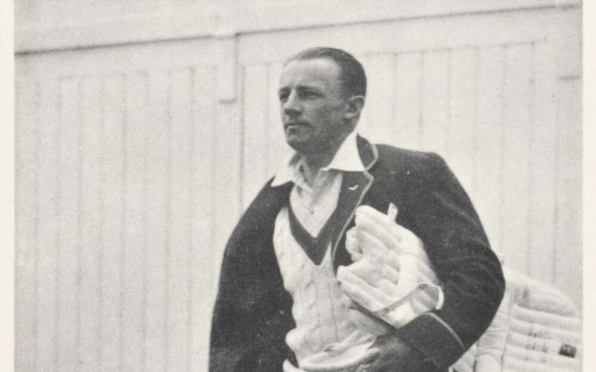 A black and white signed photo of Don Bradman walking onto the oval with his pads and cricket bat.