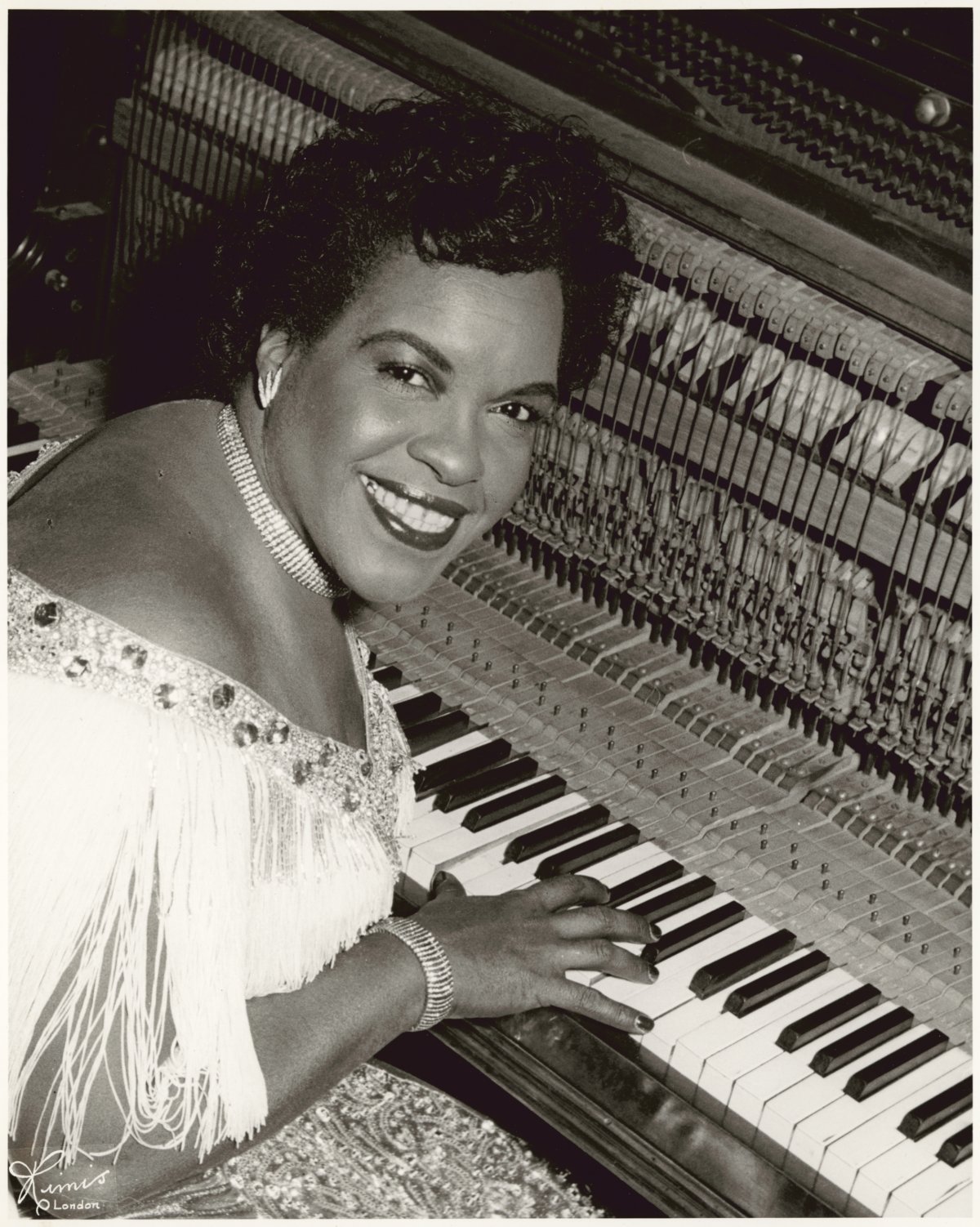 A woman sits at a keyboard and smiles at the camera.