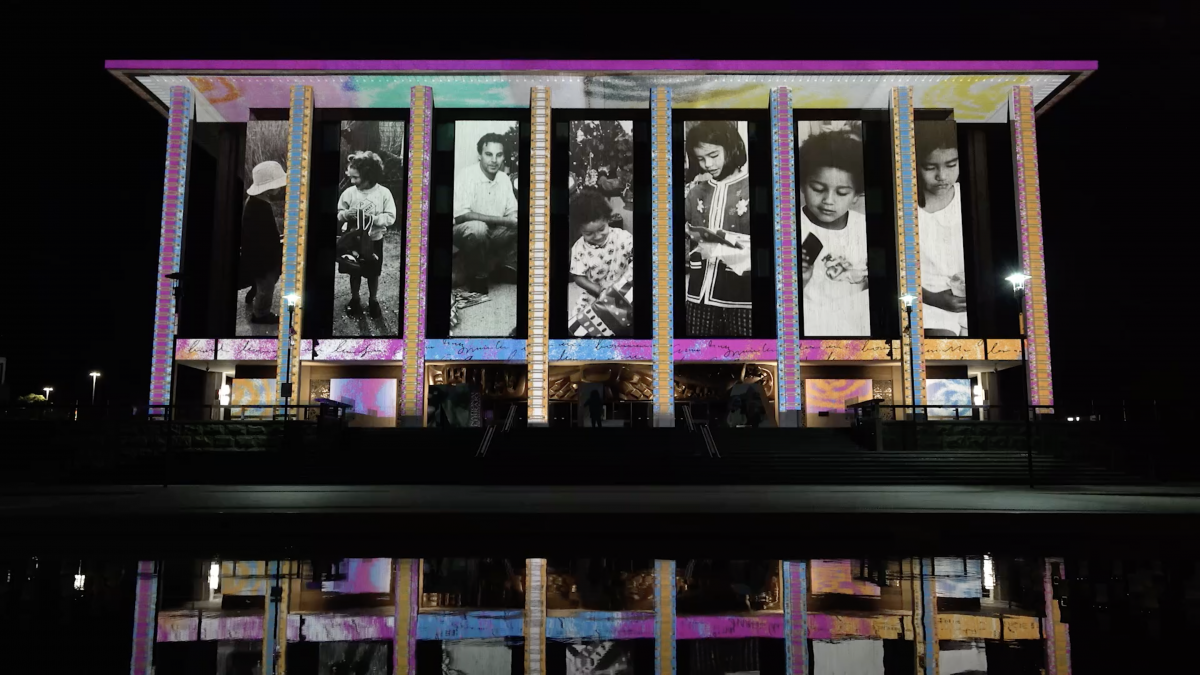 Enlighten projection showing a series of black and white family photos on National Library building 