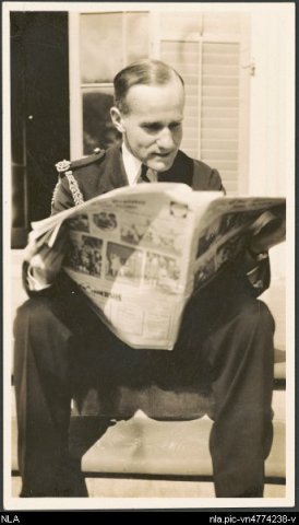 Unidentified aviator in uniform sitting on steps reading a newspaper, ca. 1930 [picture]. 