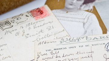 Handwritten postcards and sketches are piled up on top of each other for display