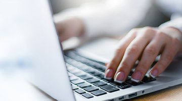 Photo of a woman's fingers resting on a laptop keyboard