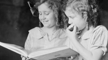 Portrait of two girls, Adelie and Toni Hurley, reading a book