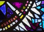 Detail photograph of stained glass window with blue, purple, pink and yellow panes