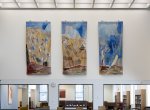 Three vertical artworks hang above a large entranceway with views to desks and bookshelves
