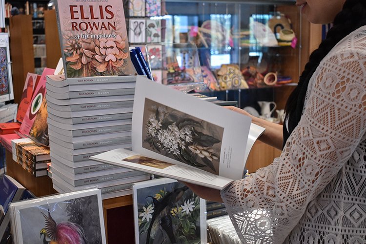 A customer flips through a book about Ellis Rowan at the National Library Bookshop
