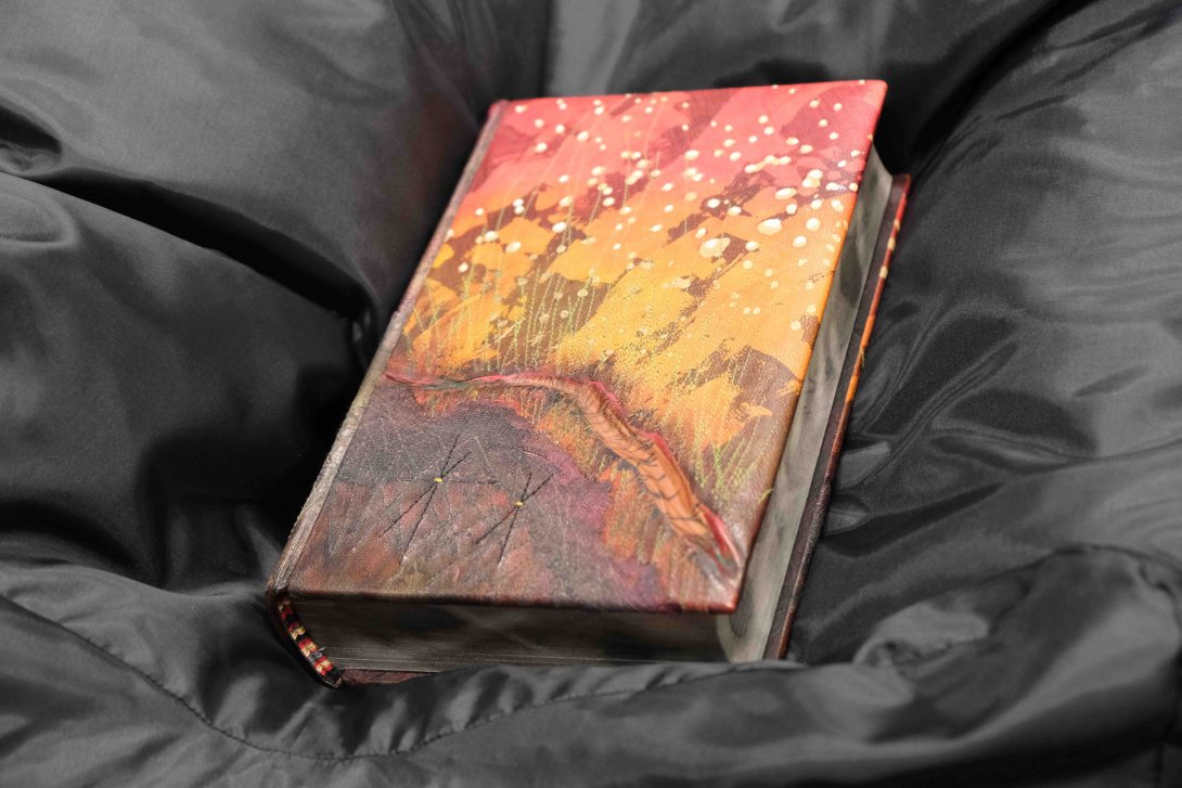 A handpainted hardback book sits in a cushioned black box