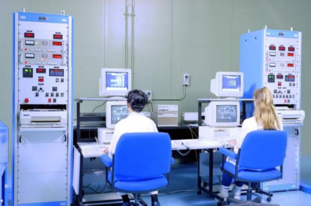 Two women in lab coats sit at computers