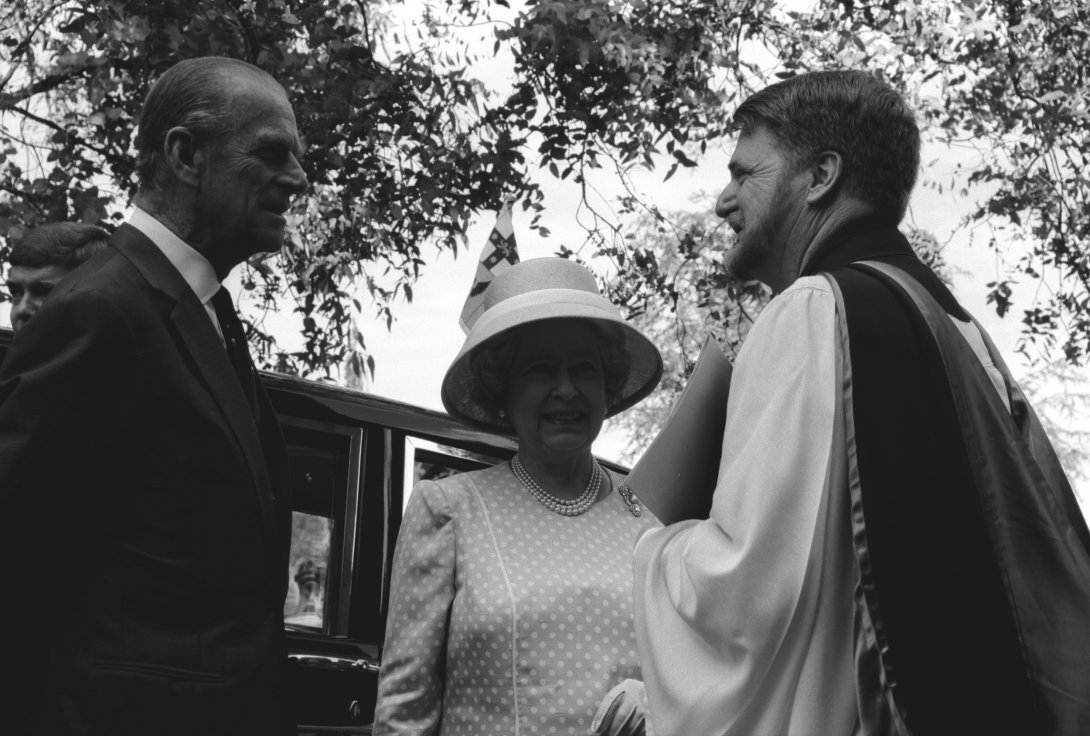 A black and white image of Queen Elizabeth and Prince Philip greeting a man in ecclesiastical robes.
