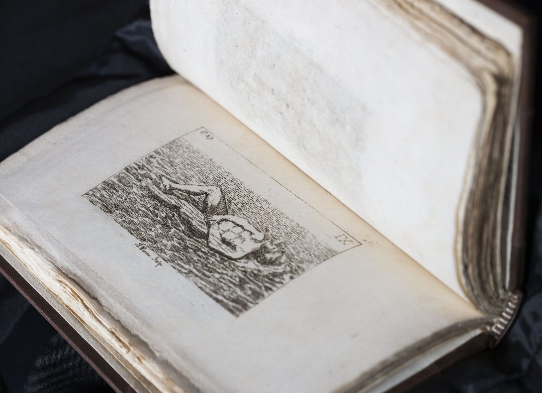 A rare book about swimming held open. Left side shows an illustrated black a white person floating on the surface of water. 