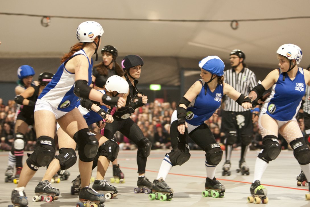 A team of Rolly Derby players trying to prevent the opposite team from getting through them.