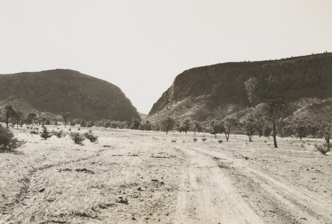 Desert road leading towards a gap in a mountain range