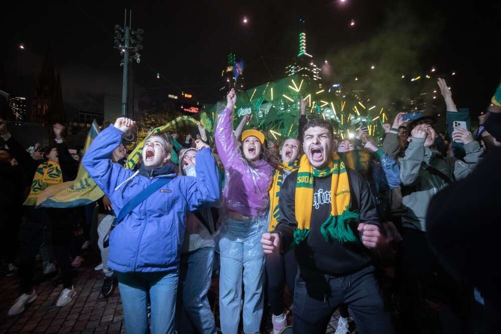 Several people at the front of a crowd jumping up and cheering.