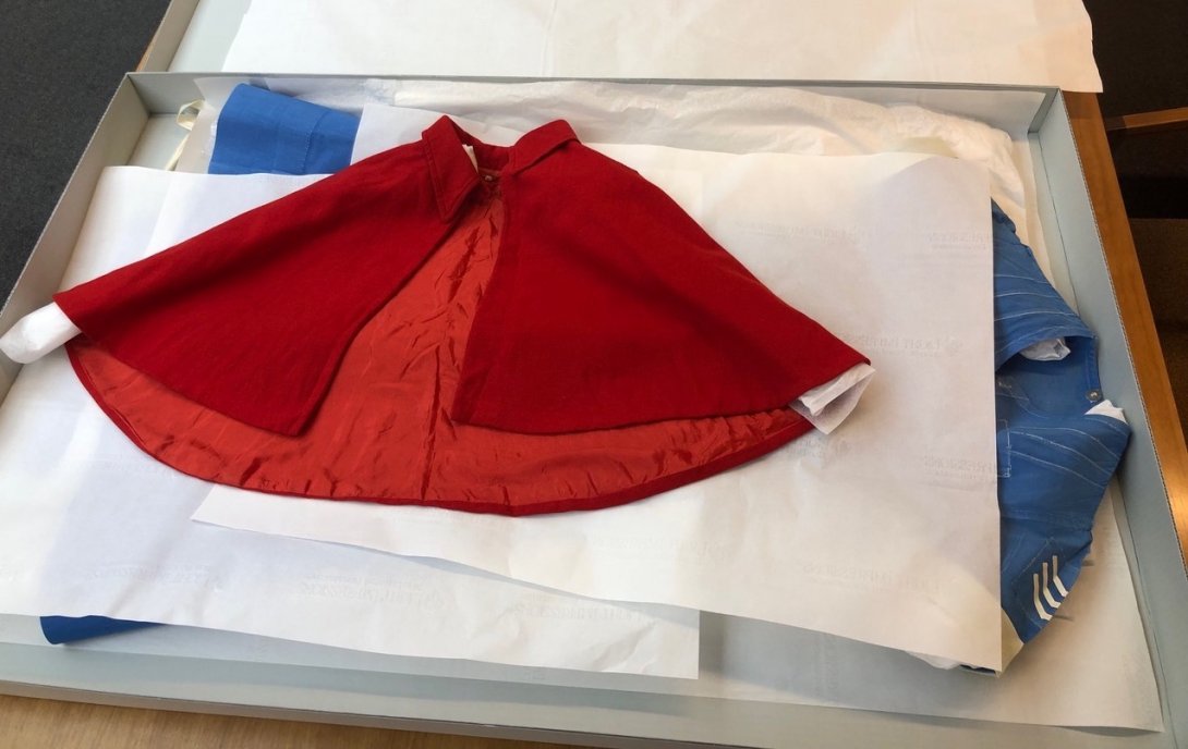 Blue nurse's uniform and red cape laid carefully in a large box